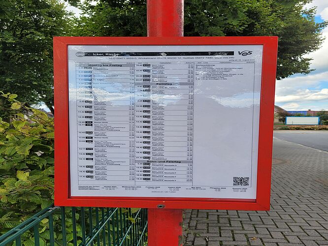Fahrplanaushang an einer Haltestelle mit QR-Code für weitere Informationen.