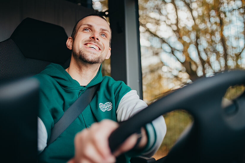 Busfahrer fährt einen Bus und lächelt