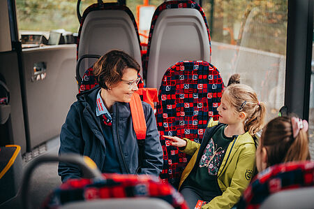 Die Bustrainerin erklärt den Kindern im Bus die optimalen Verhaltensweisen während einer Busfahrt.