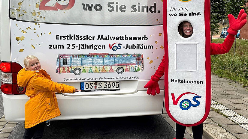 Malwettbewerbgewinnerin Jana steht vor ihrem Bild am Heck eines Busses.