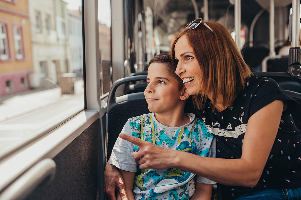 Mutter und Kind schauen im Bus aus dem Fenster.