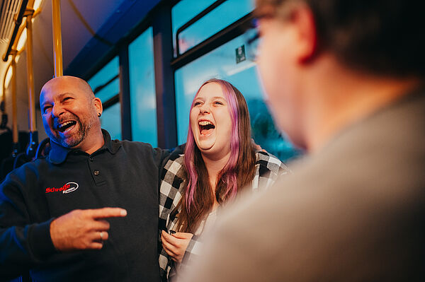 Zwei Fahrgäste halten sich in den Arm und lachen.